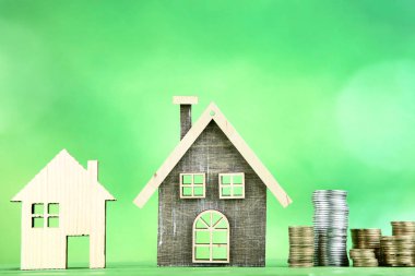 Yeşil arka plan üzerinde paralar ile ahşap ev modelleri