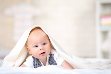 Küçük çocuk beyaz yatakta yatarken