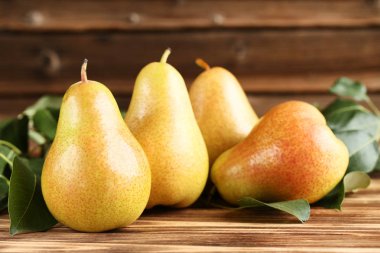 Kahverengi ahşap masada olgun armut ve yeşil yaprakların