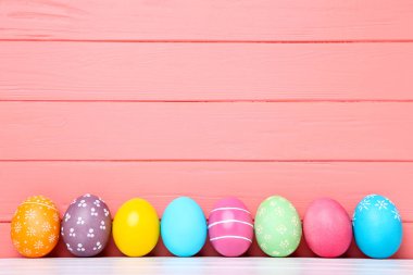 Mercan ahşap arka plan üzerinde renkli Paskalya yumurtaları