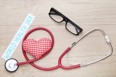 Metin Dünya Sağlık günü stetoskop, gözlük ve kumaş kalpli ahşap masa