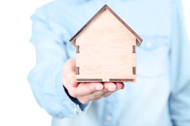 Ahşap ev modelini tutan kadın.