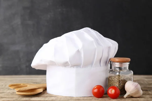 Sombrero de chef con cubiertos de madera y verduras en mesa de madera — Foto de Stock