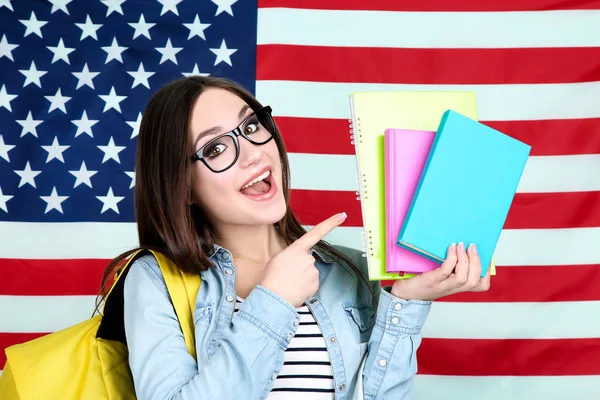 Joven estudiante con mochila y libros sobre fondos de bandera estadounidense — Foto de Stock