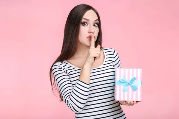 Hermosa mujer joven con caja de regalo sobre fondo rosa — Foto de Stock
