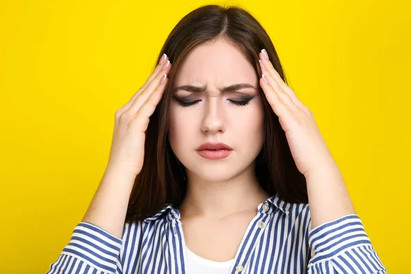 Mujer joven con dolor de cabeza sobre fondo amarillo — Foto de Stock