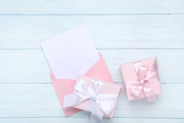 Paper envelope with gift boxes on wooden table