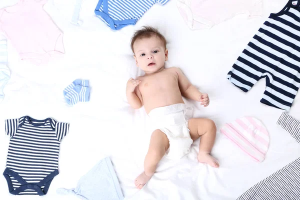 Bebê bonito com roupas de moda deitado na cama branca — Fotografia de Stock