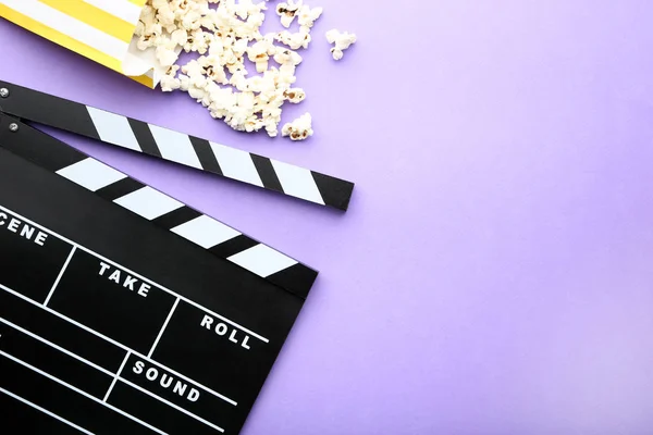 Tablero Clapper con palomitas de maíz sobre fondo púrpura — Foto de Stock