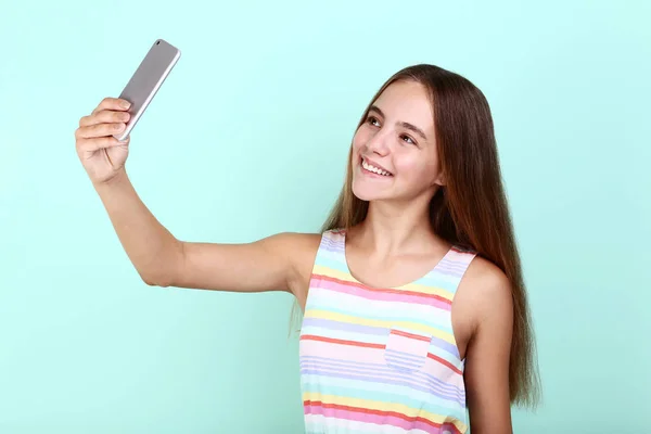 Красивая девушка делает селфи на смартфоне на фоне мяты — стоковое фото
