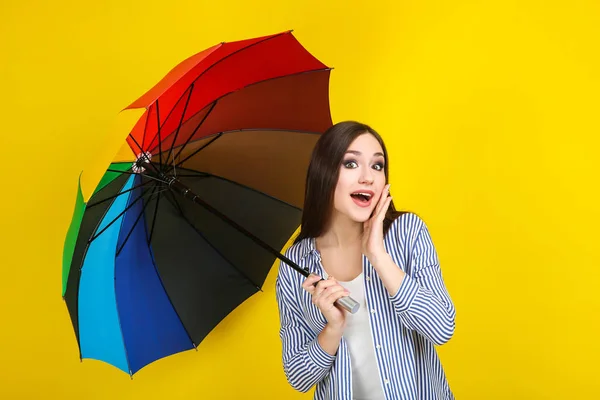 Young girl with colorful umbrella on yellow background — Stock Photo, Image
