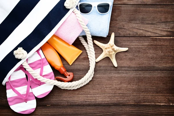 Letní taška s flip flops a ručníky na hnědý dřevěný stůl — Stock fotografie