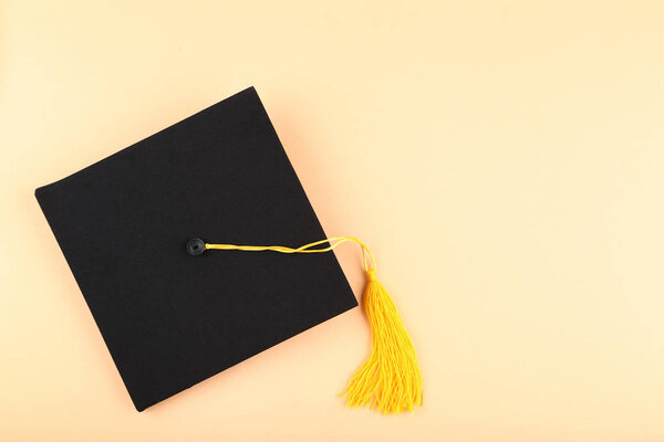 Graduation cap on beige background