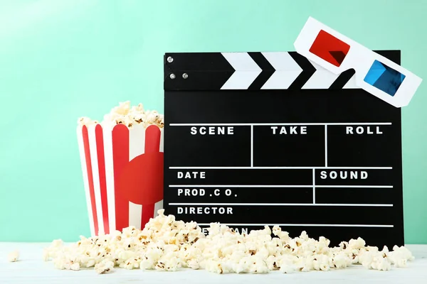 Tablero Clapper con palomitas de maíz y vasos sobre fondo de menta — Foto de Stock