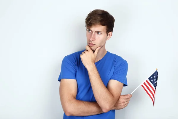 Mooie jonge man met een Amerikaanse vlag op de grijze achtergrond — Stockfoto