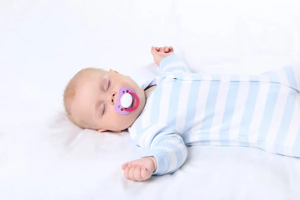 Baby boy with soother sleeping in white bed — Stock Photo, Image