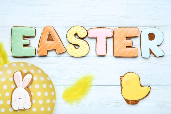 Word by Easter by gingerbread cookies and yellow feather on wood — Stock Photo, Image