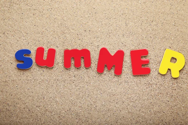 用彩色字母在沙滩上刻画夏天 — 图库照片