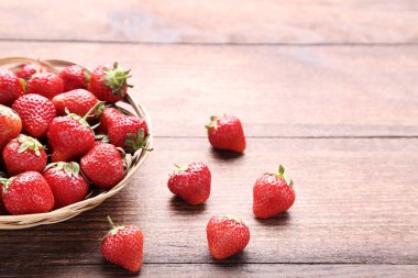 Kahverengi ahşap masa üzerinde sepet taze çilek