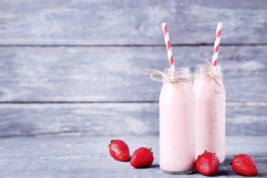 Gri ahşap masa üzerinde çilek ile cam şişelerde Smoothie