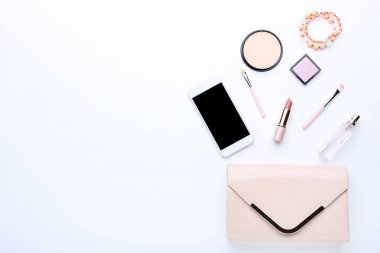 Beyaz arka planda kozmetik ve akıllı telefon ile çanta