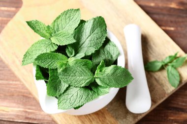 Kahverengi ahşap masada harç ile nane yaprakları