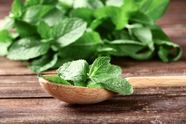 Kahverengi ahşap masa üzerinde kaşık ile nane yaprağı