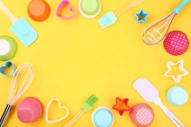Sarı arka plan üzerinde mutfak gereçleri ile Cupcake durumlarda