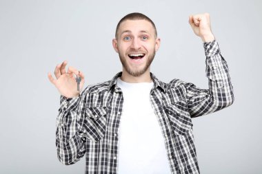 Young man holding silver key on grey background