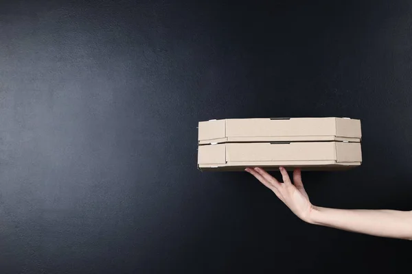 Kvinnliga hand hållande pizza boxar på Blackboard bakgrund — Stockfoto