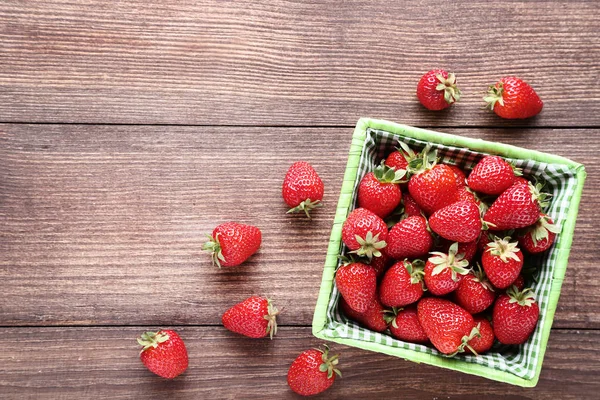 Frische Erdbeeren im Korb auf braunem Holztisch — Stockfoto