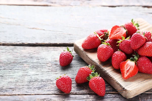 Fresas frescas con tabla de cortar sobre mesa de madera gris — Foto de Stock