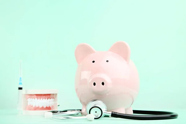 Pink piggy bank dengan stetoskop dan model gigi pada backgro mint — Stok Foto