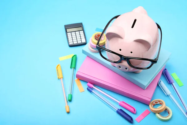 青いバックグロにメガネと学用品とピンクの貯金箱 — ストック写真