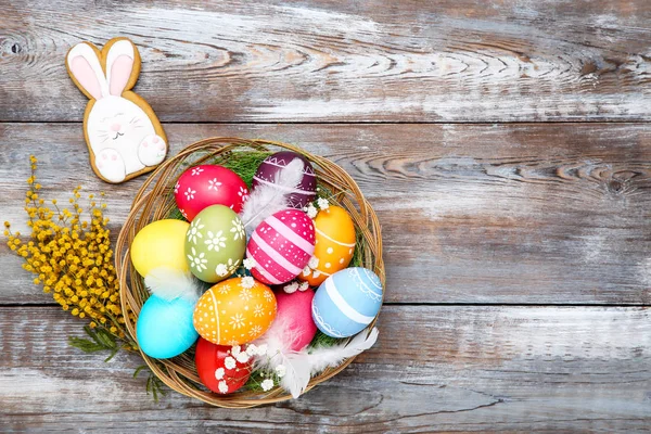 Œufs de Pâques colorés dans le panier avec des fleurs et du pain d'épice cuisinier — Photo