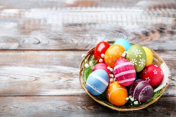 Huevos coloridos de Pascua en cesta con flores de gypsophila en marrón — Foto de Stock