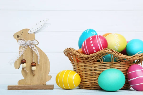 Beyaz arka planda ahşap tavşanlı renkli paskalya yumurtaları — Stok fotoğraf