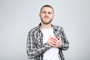 Young man having heartache on grey background