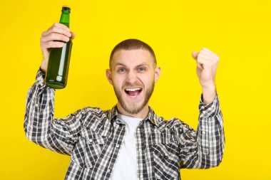 Sarı arka planda bira şişesi ile genç adam