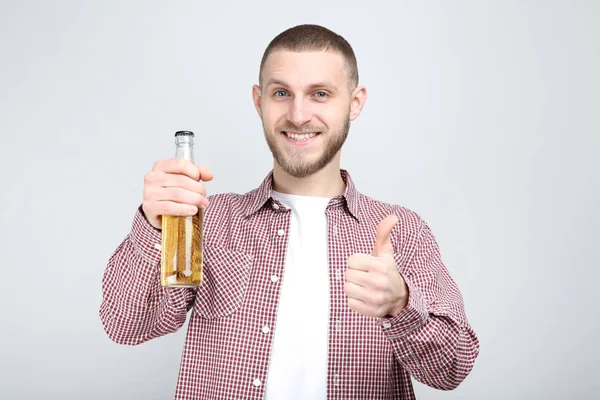 Jeune homme avec bouteille de bière sur fond gris — Photo