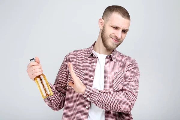 Молодий чоловік з пляшкою пива на сірому фоні — стокове фото