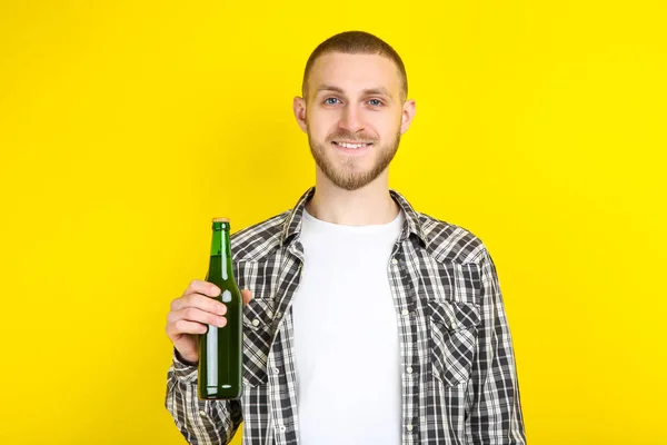 Jonge man met fles bier op gele achtergrond — Stockfoto