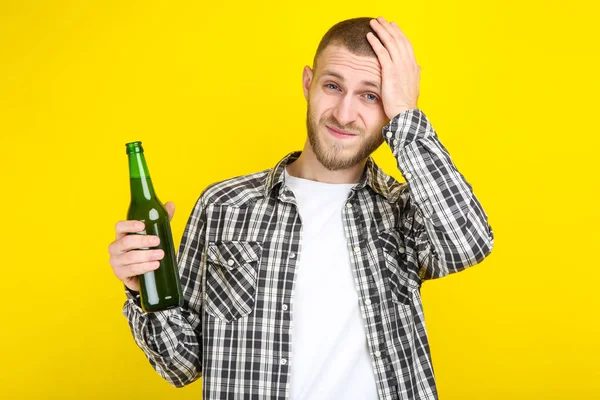 Молодий чоловік з пляшкою пива на жовтому фоні — стокове фото