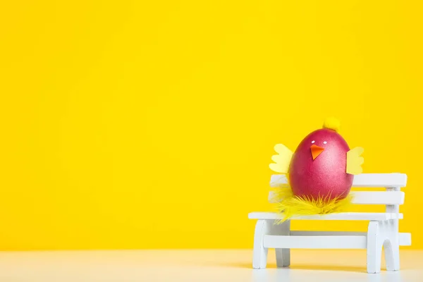 Śliczne wielkanocne jajko z białą ławką na żółtym tle — Zdjęcie stockowe