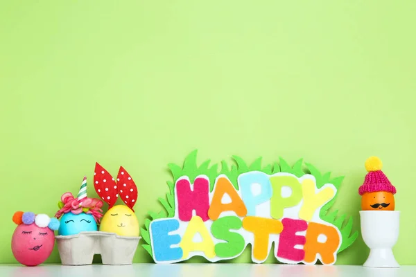 Huevos lindos con texto Feliz Pascua sobre fondo verde — Foto de Stock