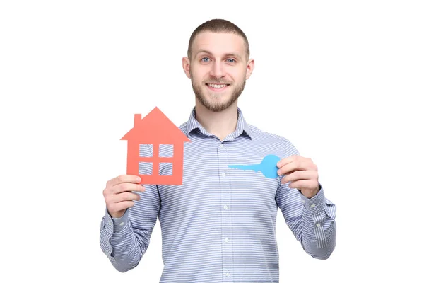 Jeune homme avec maison en papier et clé sur fond blanc — Photo