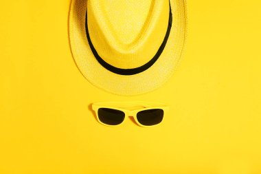 Sarı arka planda şapkalı güneş gözlüğü. Minimalizm kavramı