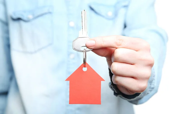 Female hand holding silver key with red paper house