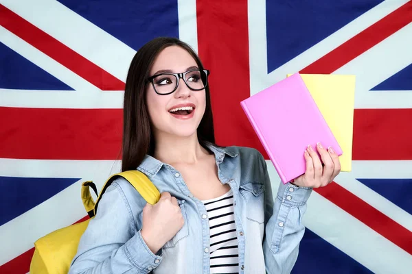 Young student with backpack and books on British flag background