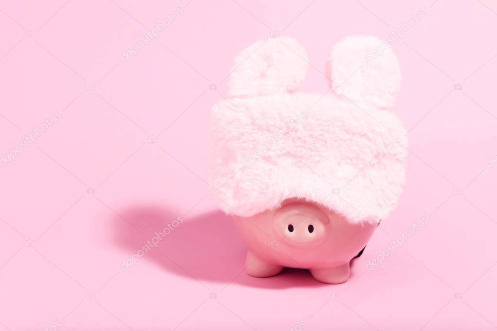 Piggybank with sleeping mask on pink background. Minimalism concept